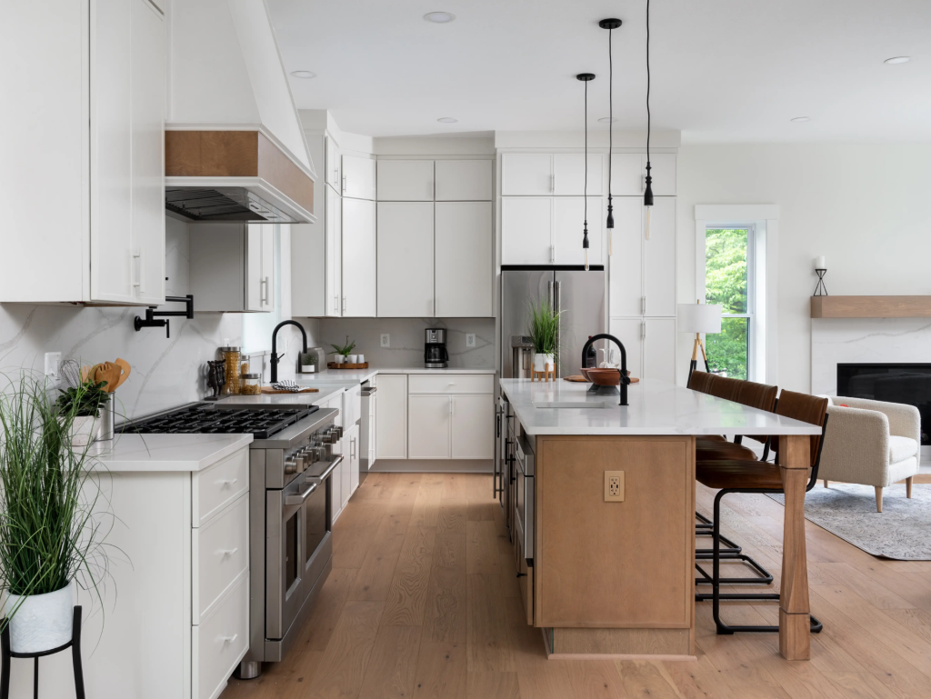 Spacious kitchen remodel featuring a large center island with seating, custom cabinetry, modern pendant lighting, and an open-concept layout filled with natural light.